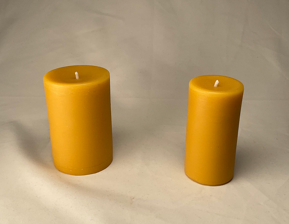 Two yellow candles on a plain background